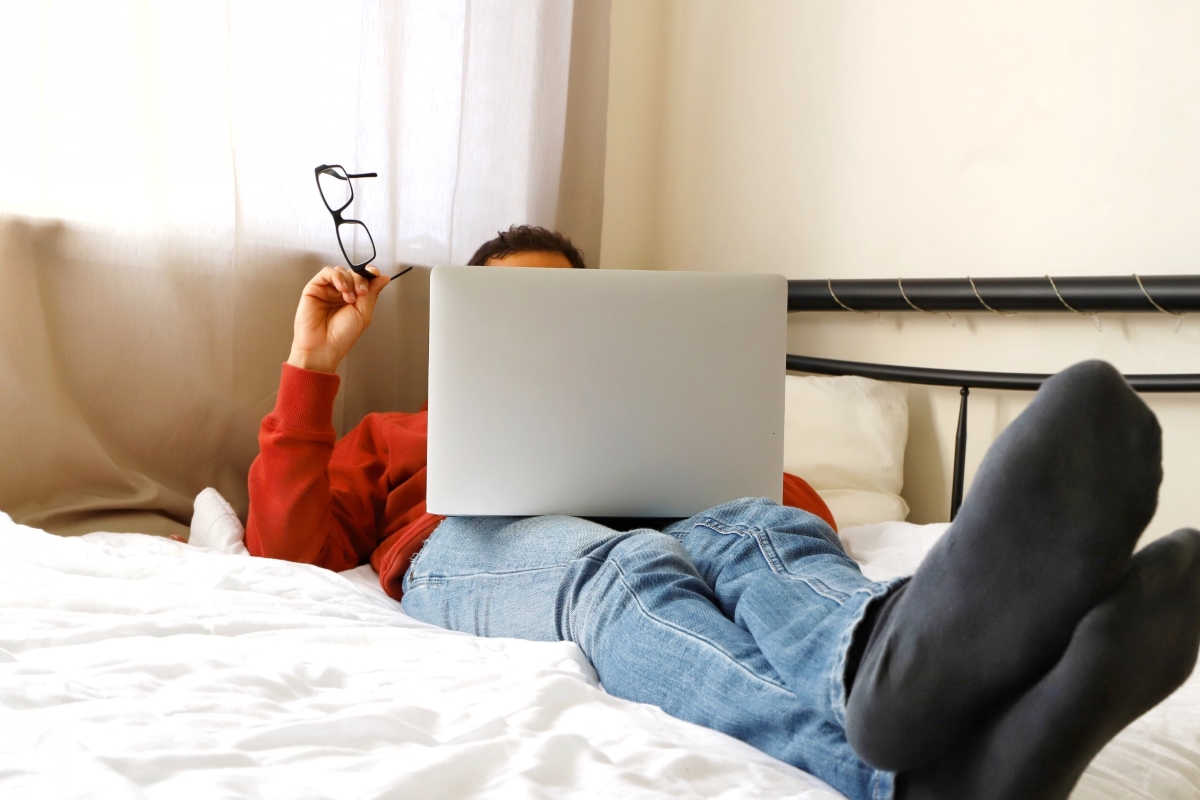 a-millennial-guy-sitting-on-the-bed-and-using-the-laptop-while-working-from-home-remote-work_t20_NGZ1Jl